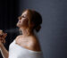 An image of a lady applying perfume to her neck